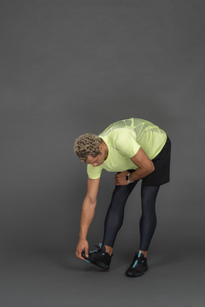 Athletic man bending over and touching his running shoes