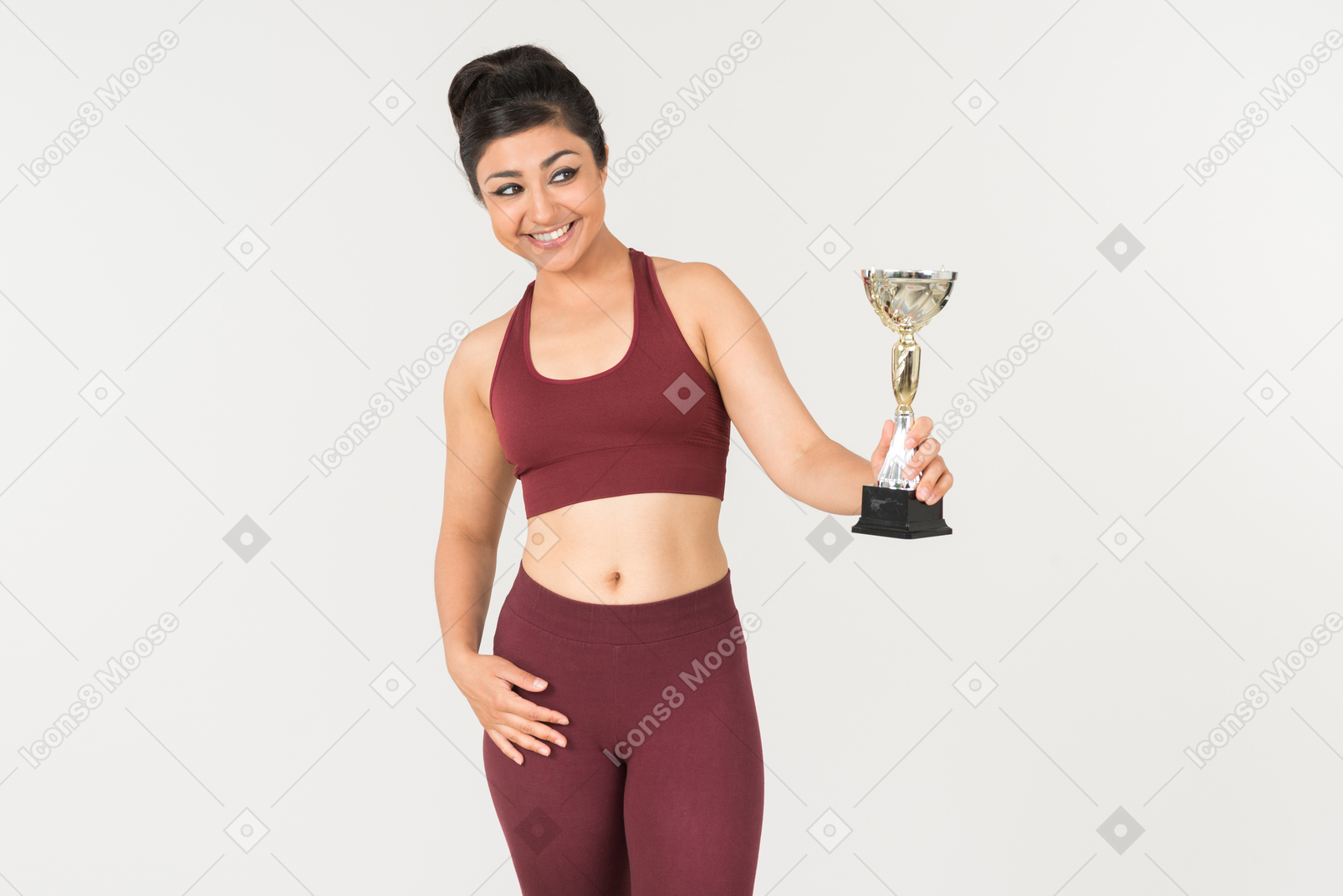 Young indian woman in sportswear holding award cup