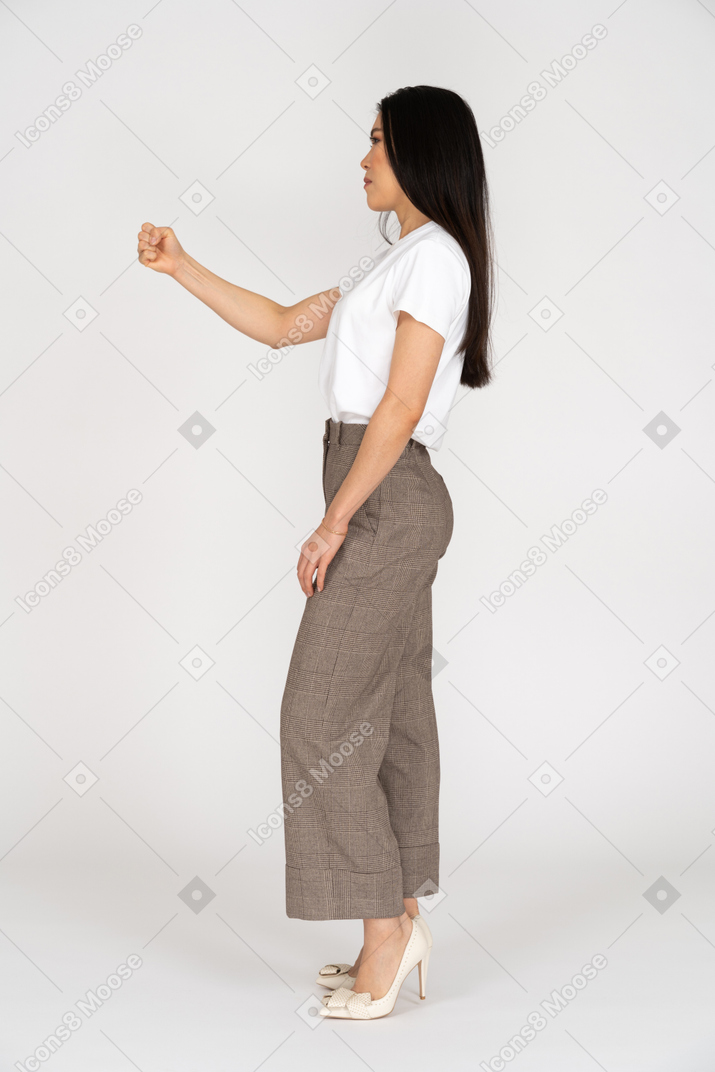 Vista laterale di una giovane donna in calzoni stringendo il pugno