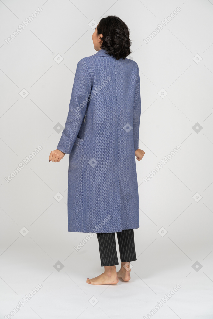 Back view of a woman in coat standing with clenched fists