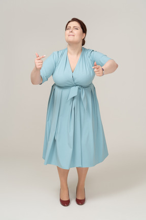 Front view of a happy woman in blue dress dancing