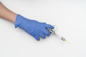 Hand in protective glove holding a syringe