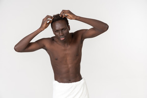 A young black man with a white bath towel around his waist doing his morning routine