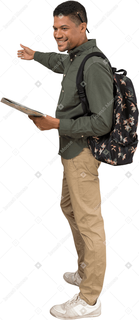 Вид сбоку человека с рюкзаком и картой, показывающей направление и улыбающегося