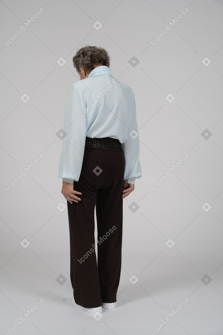 Three-quarter back view of an old woman slouching