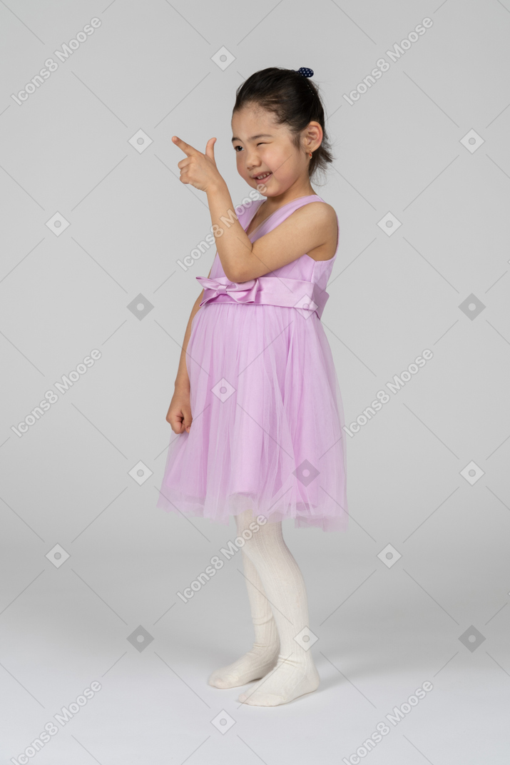 Menina de vestido rosa apontando com uma arma de dedo