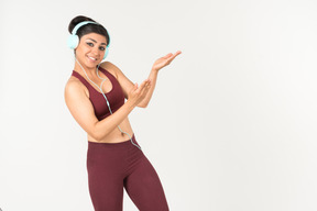 Laughing young indian woman in sporstwear listening to music in headphones