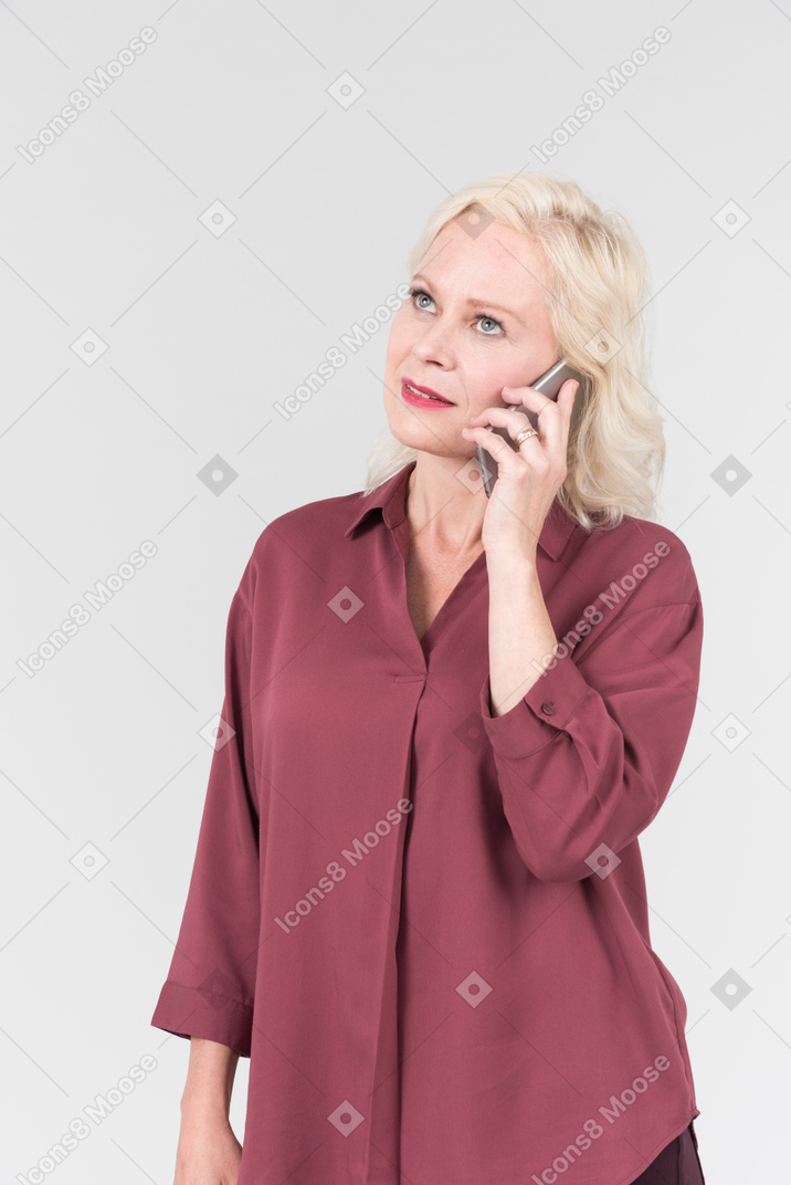 A nice-looking middle-aged blonde woman in a burgundy shirt talking by the phone