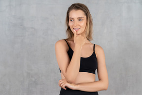 Mujer con ropa deportiva negra tocándose el labio y mirando a un lado