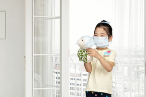 Little girl and her toy wearing face masks