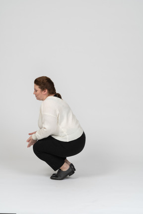 Side view of a plump woman in casual clothes squatting