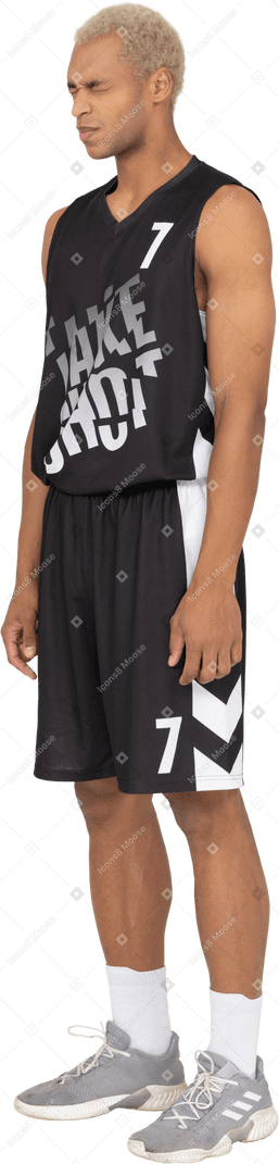 Vista de três quartos de um jovem jogador de basquete descontente com os olhos cerrados