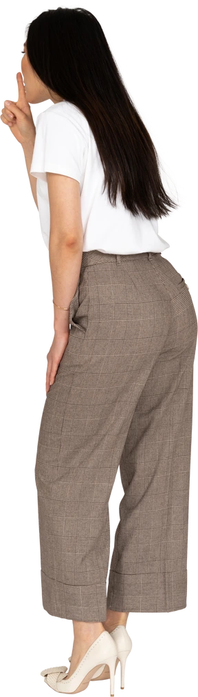 Three-quarter back view of a young lady in breeches and t-shirt showing a silence gesture