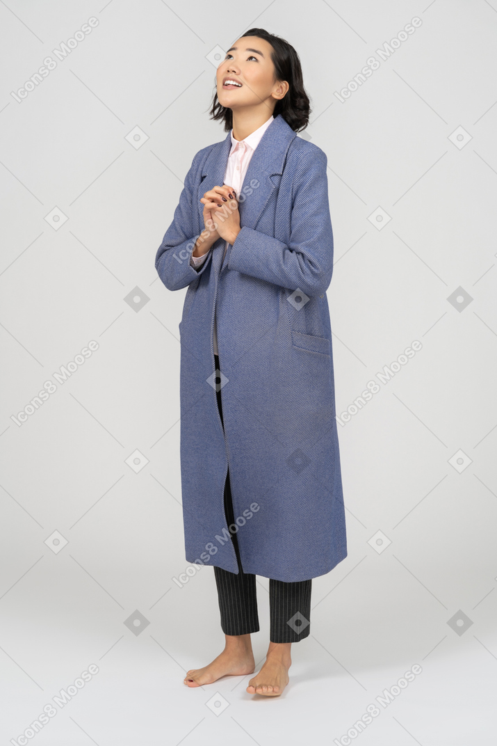 Femme gaie en manteau avec les mains jointes