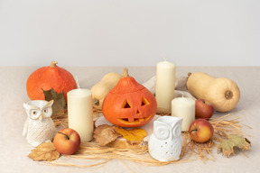 Carved pumpkins, owls figures, candles and red apples