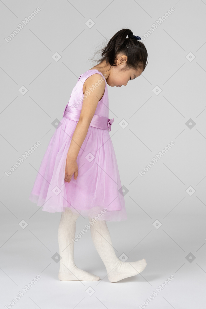 Fille en robe rose regardant son pas