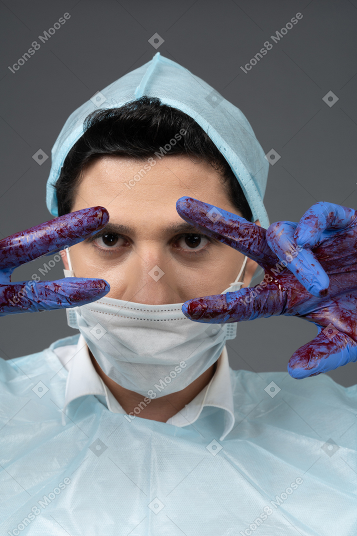 Doctor showing peace sign with bloody hands