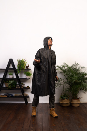 Man in raincoat catching raindrops onto palm