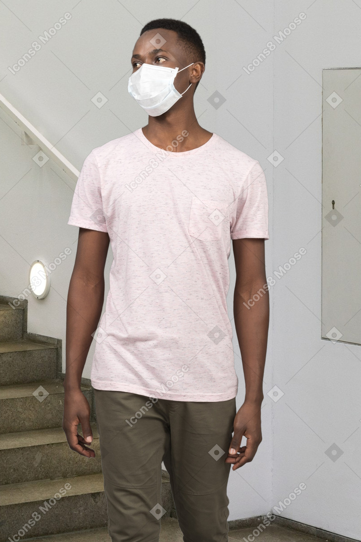 A man wearing a face mask while standing in front of stairs