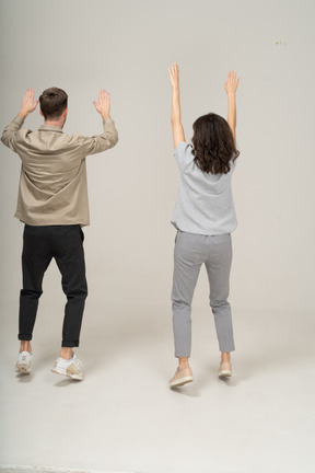 Back view of young man and woman with raised hands