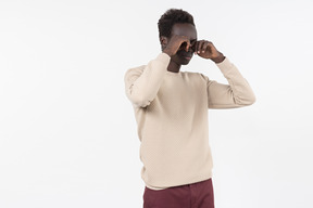 A young black man in a grey sweater standing alone on the white background