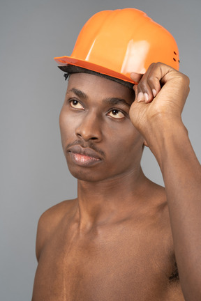 Naked young man wearing construction helmet