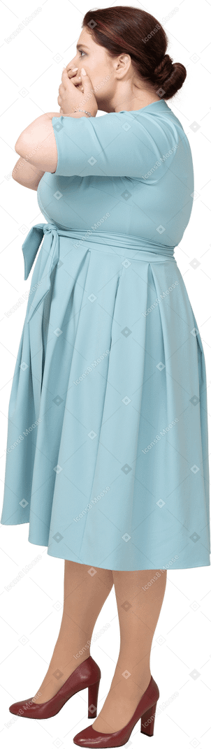 一个穿着蓝色连衣裙的女人用手捂住嘴的侧视图