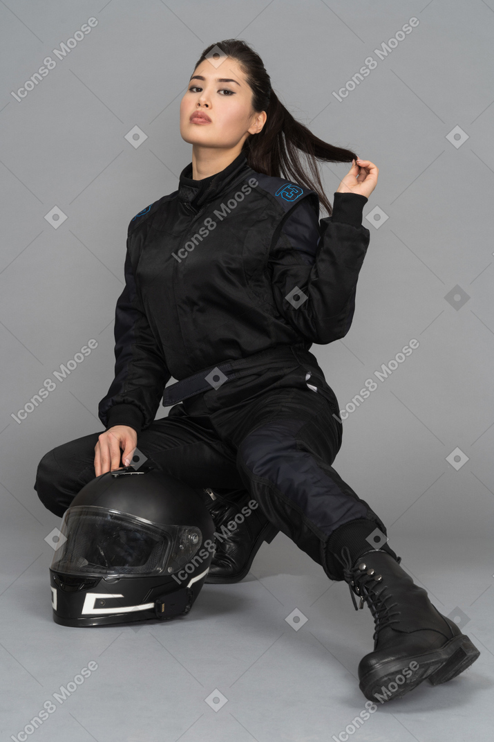 A female biker squatting on haunches and touching her hair