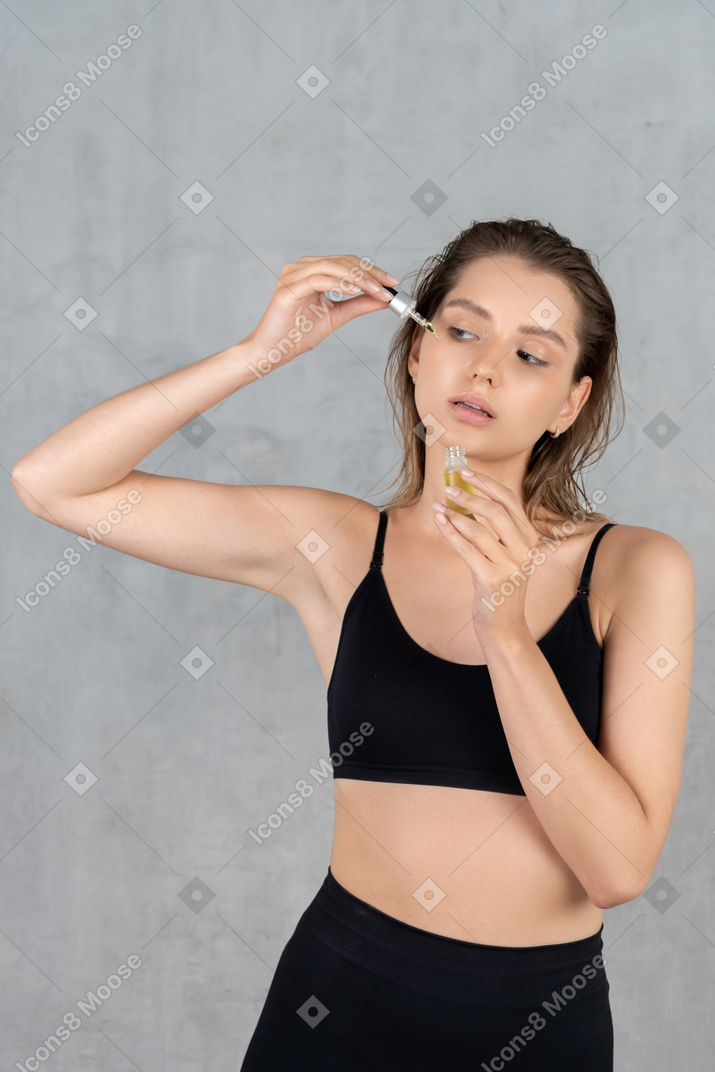 Vue de face d'une jeune femme utilisant un sérum pour le visage