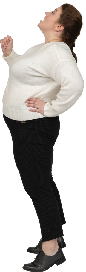 Vista lateral de uma mulher gorda em roupas casuais olhando para cima