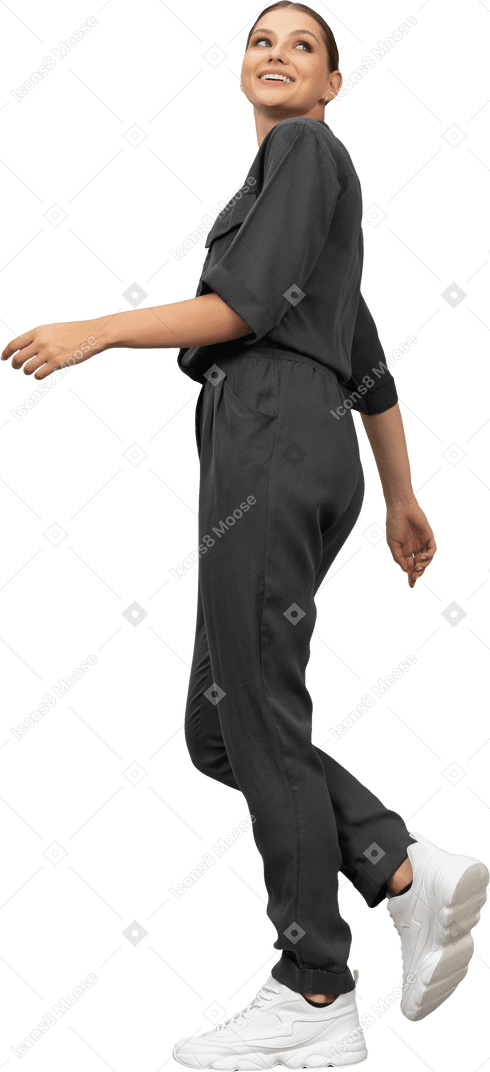 Side view of a smiling walking young woman in a jumpsuit