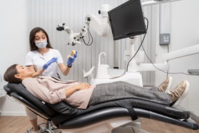 Full-length of a female dentist showing teeth prototype to female patient in a hospital cabinet