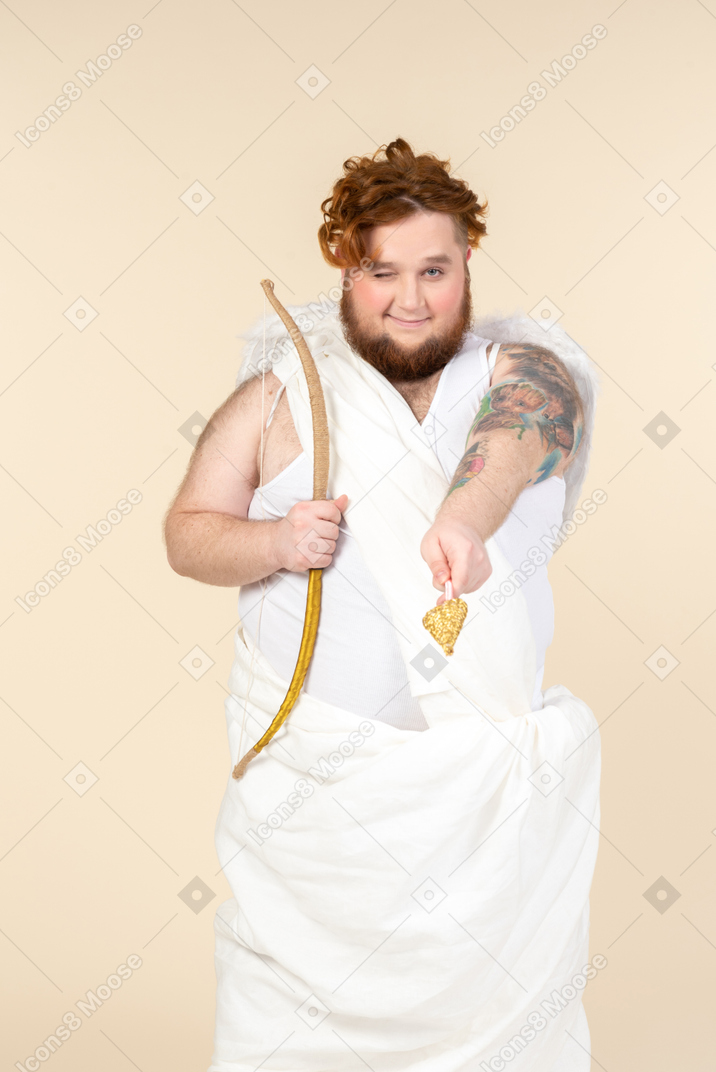 Young big man dressed as a cupid pointing with an arrow