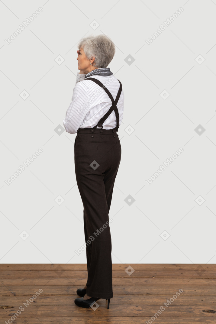 Three-quarter view of an old lady in office clothing touching her head