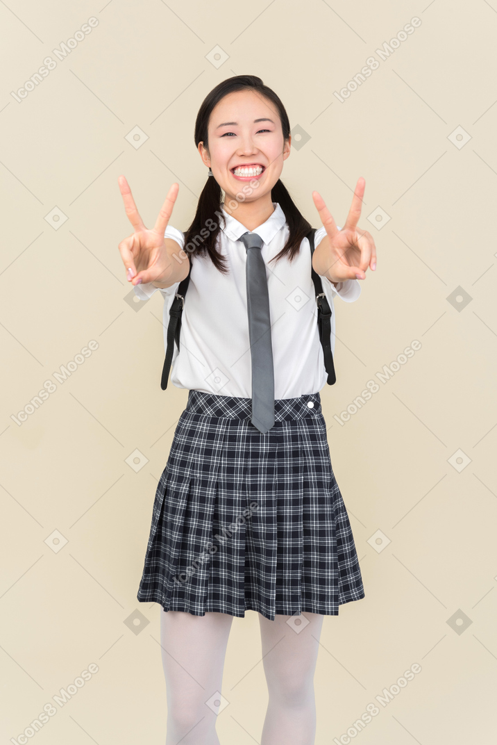 Menina da escola asiática mostrando sinal de vitória