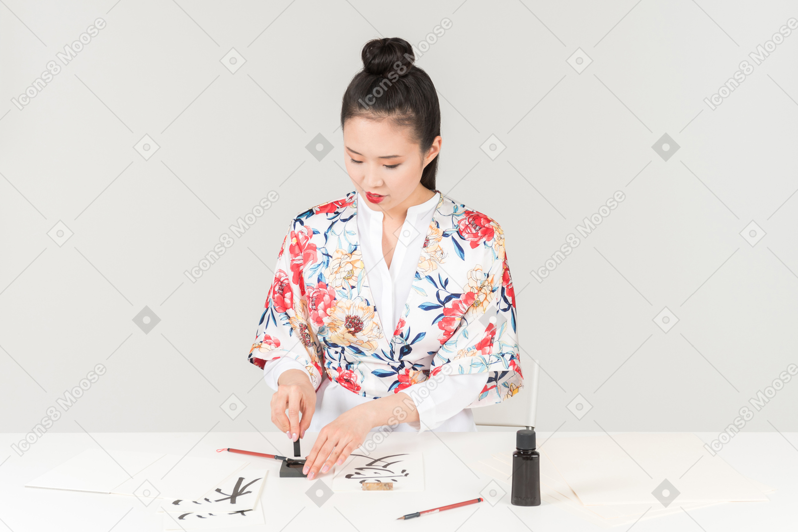 Giovane donna in un colorato kimono giapponese impara la calligrafia disegnando un geroglifico