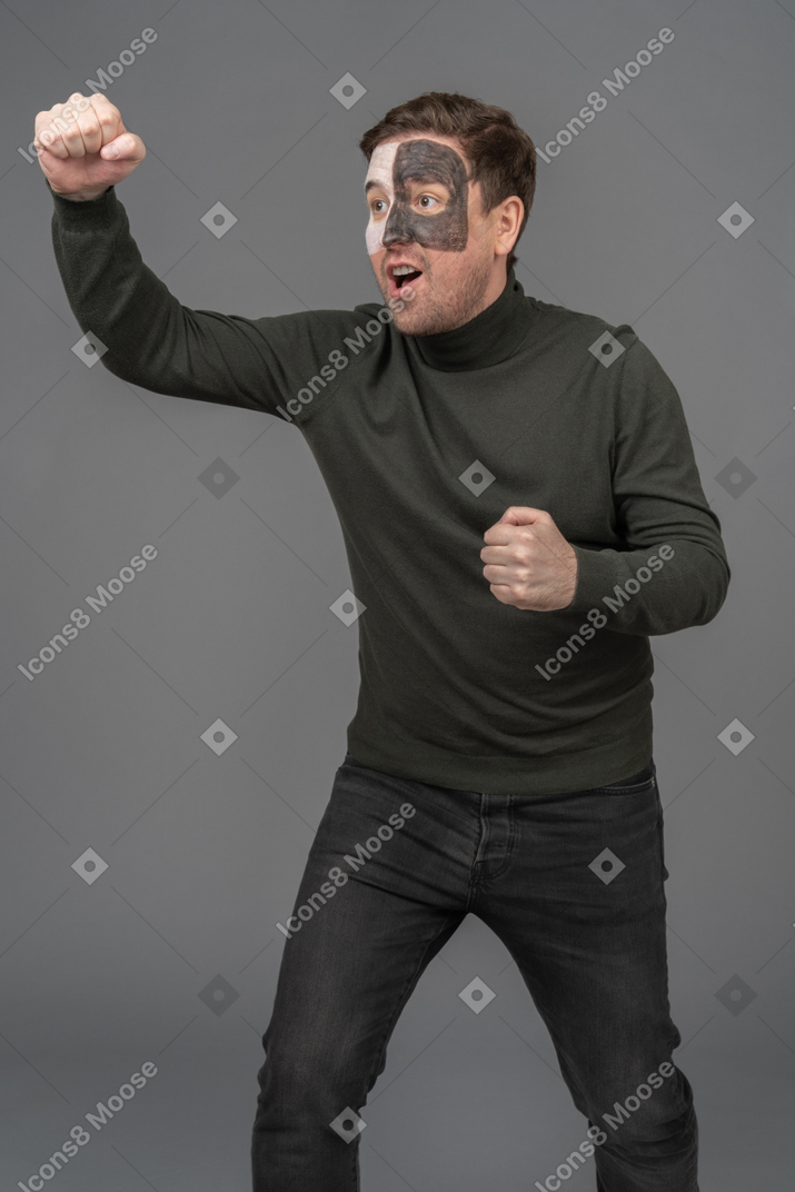 Three-quarter view of a cheerful male football fan raising hand & clenching fists