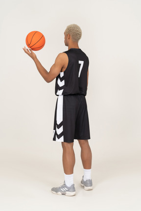 Vue de trois quarts arrière d'un jeune joueur de basket-ball tenant un ballon