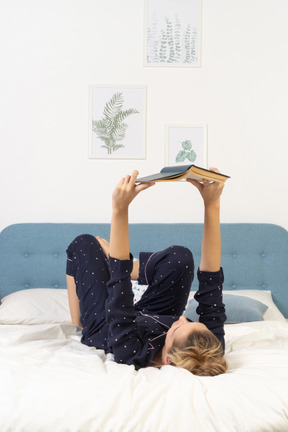 Full-length of a bored young lady trying to read book in bed