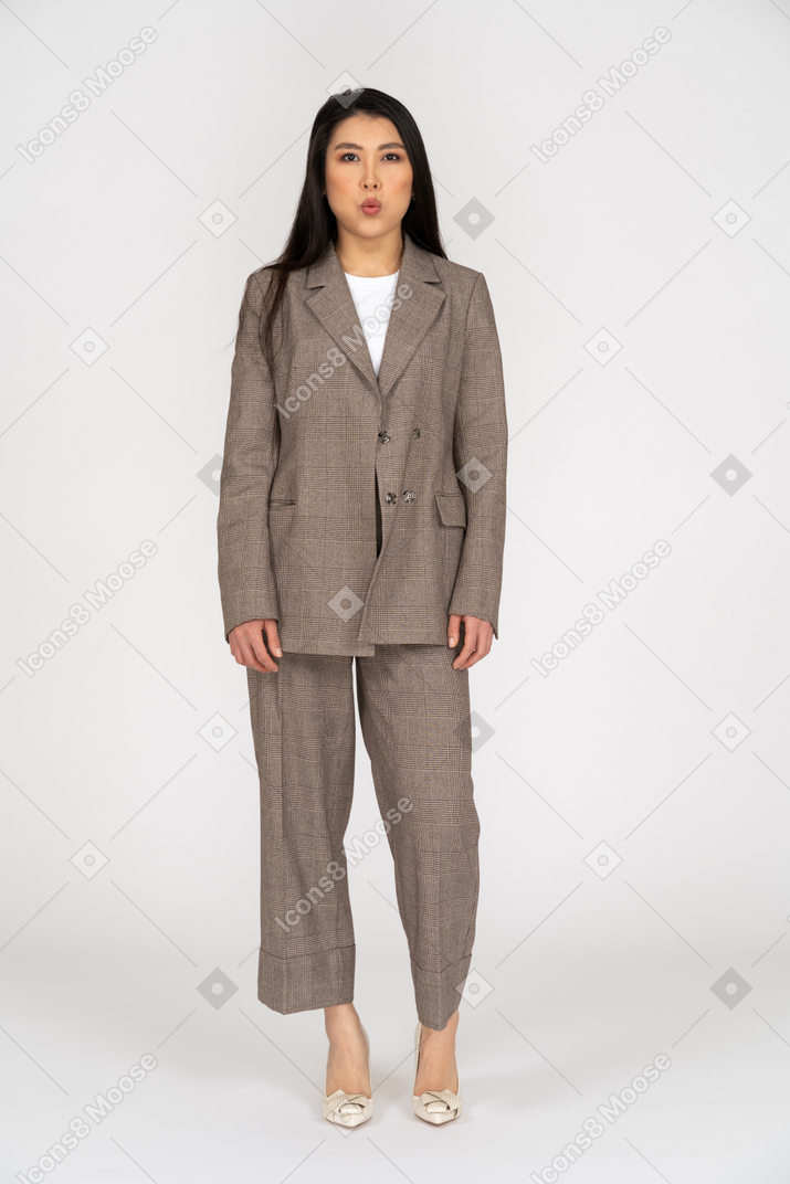 Front view of a young lady in brown business suit blowing cheeks