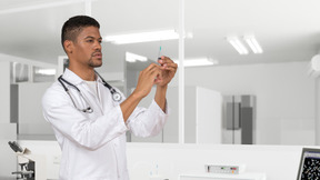 Doctor in a white coat is holding a syringe