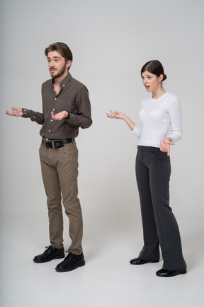 Three-quarter view of a questioning young couple in office clothing