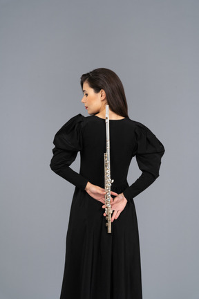 Back view of a young lady in black dress holding flute behind