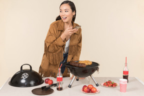 Jeune fille asiatique debout près de la grille et faire une photo de barbecue