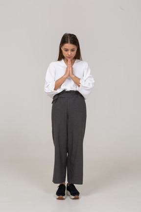 Front view of a praying young lady in office clothing holding hands together