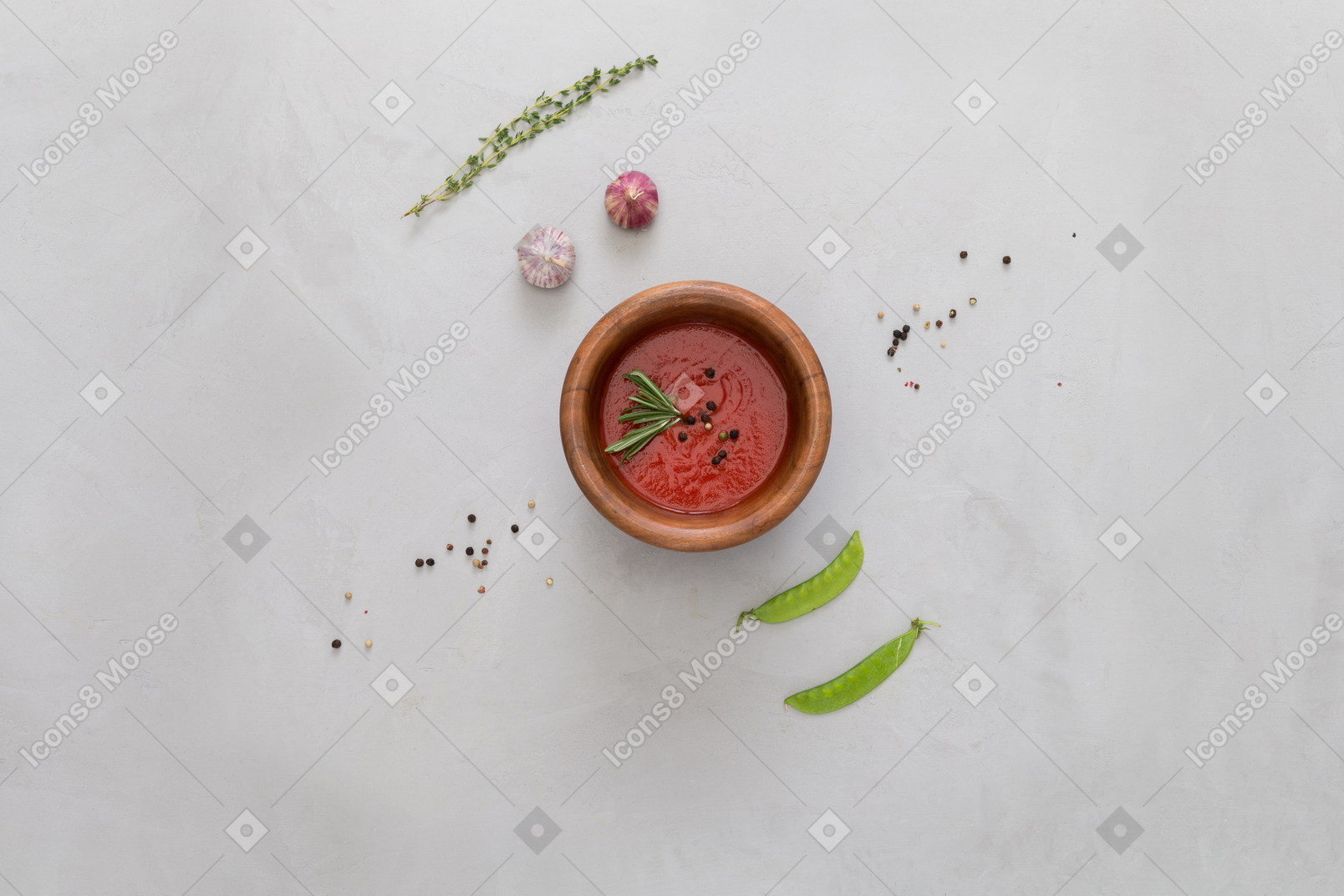 A bowl of gazpacho, some garlic, green peas
