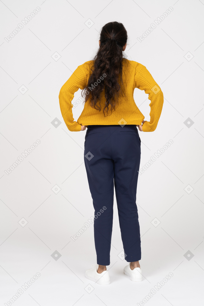 Vista posteriore di una ragazza in abiti casual in piedi con le mani sui fianchi