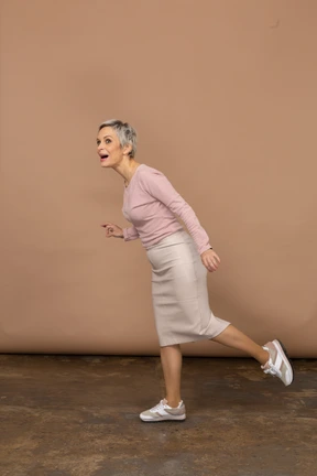 Impresionada mujer en ropa casual de equilibrio sobre una pierna