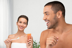 Homem e mulher escovando os dentes