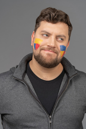 Front view of a male football fan with colorful face art